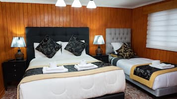 Habitación de hotel con dos camas, paneles de madera y un amplio ventanal con persianas.