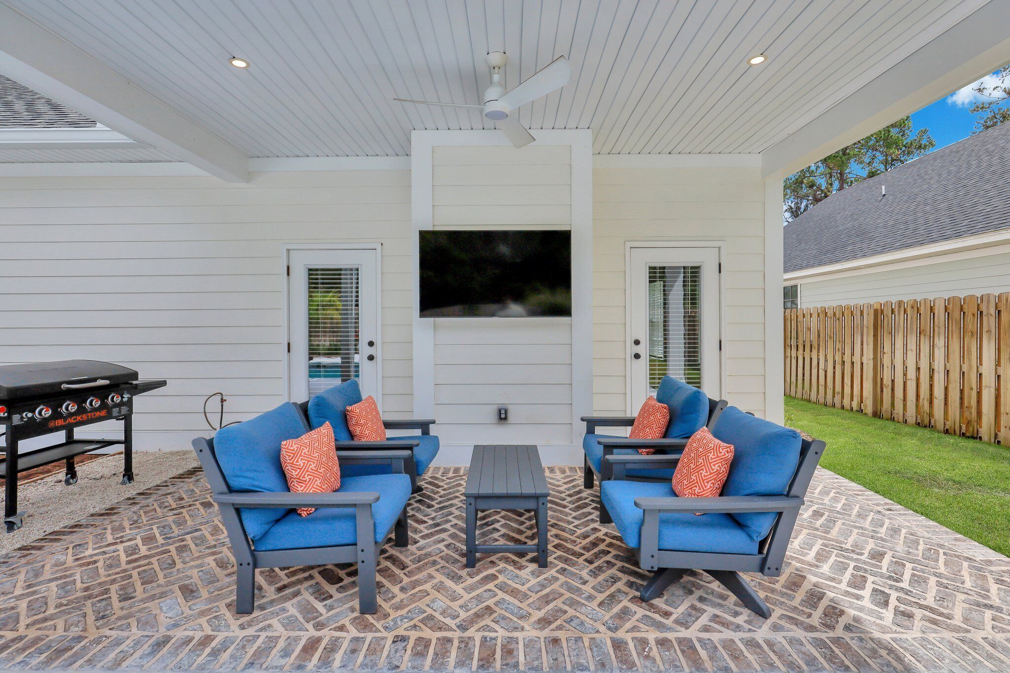 Une terrasse extérieure avec deux chaises bleues, une petite table et un ventilateur de plafond.