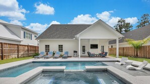 A backyard with a swimming pool, lounge chairs, and a covered patio area. - Private Heated Pool & Spa | Close to Beaches, Restaurants & Shopping! (Saint Simons Island)