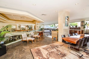 Relax in our elegant lobby, featuring a spacious reception area with a polished desk, comfortable seating, and a large wooden table for meetings or dining.