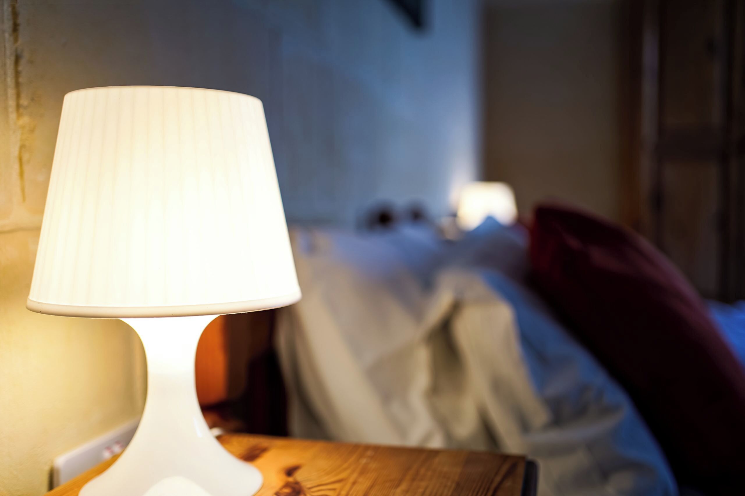 En lampa på ett sidobord i ett svagt upplyst rum.