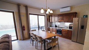Une cuisine moderne avec un coin repas, de grandes fenêtres et une vue sur une piscine.