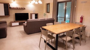 Een moderne woonkamer met een bank, televisie, houten eettafel en stoelen.