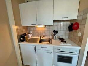 Een koelkast, een oven, een broodrooster, kookgerei, borden en bestek