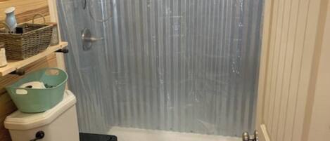 Un baño pequeño con ducha, inodoro y lavabo.