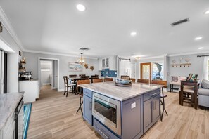 A modern kitchen with a central island, built-in oven, and blue cabinetry.