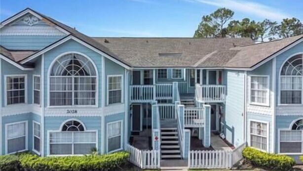 A two-story house with a porch, a staircase, and a small garden. - Spacious Condo Near Disney (Kissimmee)