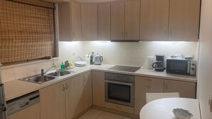 A modern kitchen with light wood cabinets, a stainless steel sink, a built-in oven, and a microwave. - Secret Arkadia Bay Beachfront, Sea & mountain View, Secret Arkadia Bay Beachfront, Sea & mountain Vi (Arkadiko Chorio)