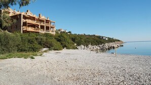 A coastal property with a large house featuring multiple balconies, a gravel beach, and a clear view of the sea. - Secret Arkadia Bay Beachfront, Sea & mountain View, Secret Arkadia Bay Beachfront, Sea & mountain Vi (Arkadiko Chorio)