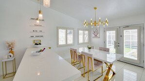 A modern kitchen with a white island, gold-framed chairs, and pendant lighting. - Indio Oasis with pool, jacuzzi, gazebo , grill, fire pit and a game room (Indio)