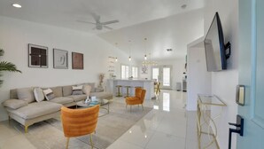 A spacious living room with a sofa, two armchairs, a coffee table, and a TV mounted on the wall. - Indio Oasis with pool, jacuzzi, gazebo , grill, fire pit and a game room (Indio)