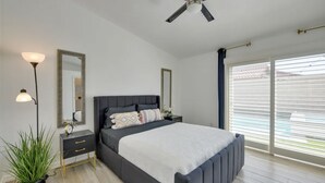 A modern bedroom with a large bed, bedside tables, a floor lamp, and a ceiling fan. - Indio Oasis with pool, jacuzzi, gazebo , grill, fire pit and a game room (Indio)