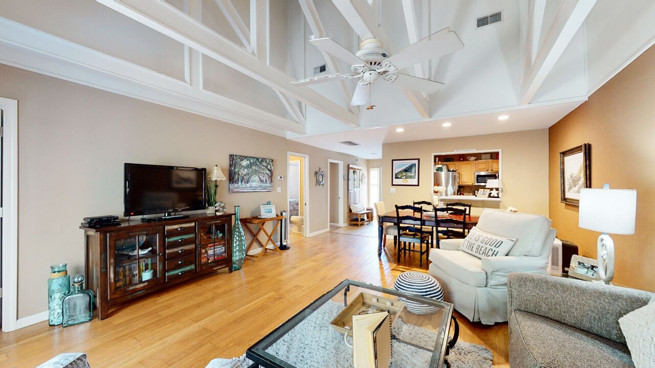 A spacious living room with a television, wooden cabinet, and seating area.