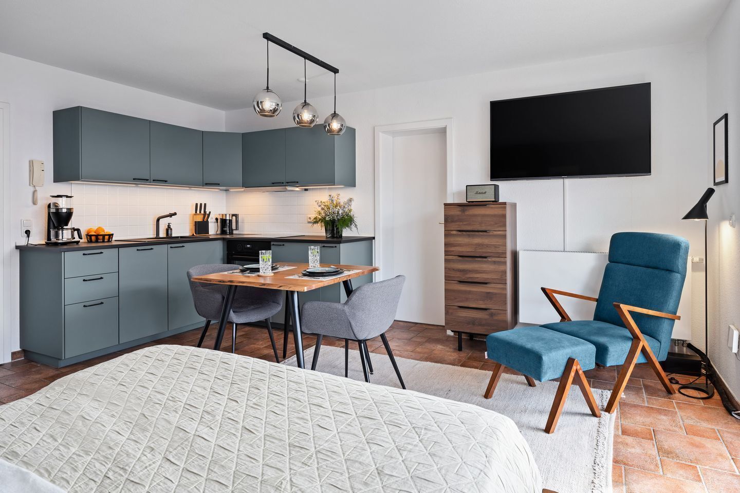 Une cuisine moderne avec des meubles de couleur grise, une table à manger en bois et deux chaises grises.