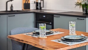 A modern kitchen with grey cabinets, a wooden dining table set with plates, glasses, and cutlery.