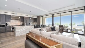 Ein modernes Wohnzimmer mit einem großen Sofa, einem Holztisch und einer Küchenzeile mit einer Marmorinsel.