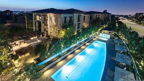 Ein modernes Gebäude mit Schwimmbad, Außenbereich und Blick auf die städtische Skyline im Abenddämmerung.