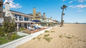 Une propriété située en bord de mer, dotée d’un patio, de chaises longues et d’un palmier.