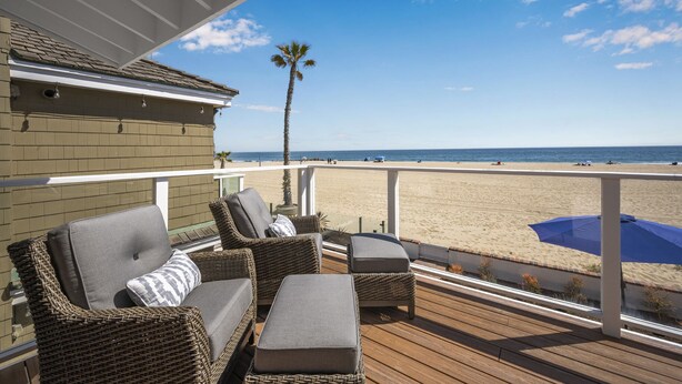 Un espace extérieur abrité, aménagé avec des meubles en osier et offrant une vue sur la plage.