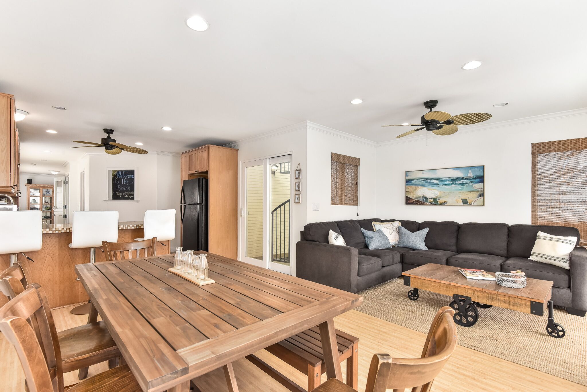 A spacious living area with a wooden dining table, a dark-colored sofa, and a ceiling fan.