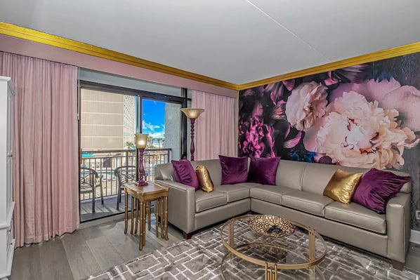 A modern living room with a sofa, a coffee table, and a large floral mural on the wall.