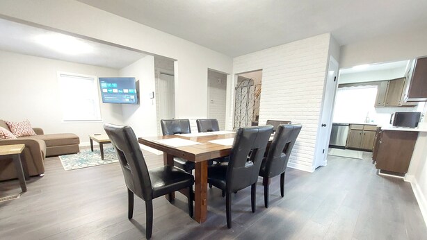 Una sala de estar moderna con una mesa de comedor, sillas, un sofá y un televisor.