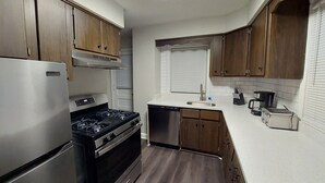 Una cocina moderna con electrodomésticos de acero inoxidable, armarios de madera y encimera blanca.