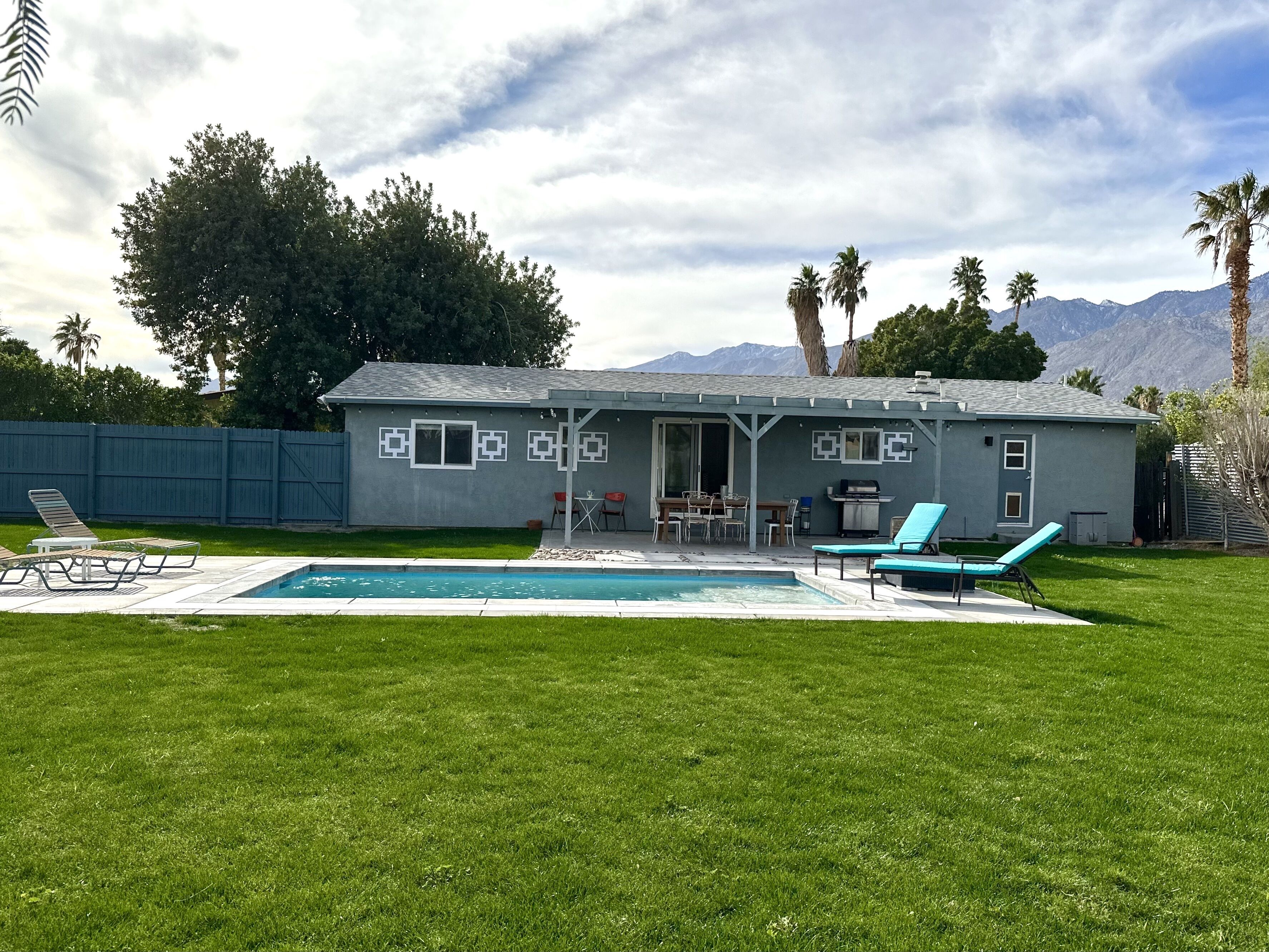 Et hus med swimmingpool, udendørs møbler og udsigt til et bjerg.