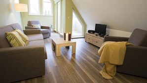 Uma sala de estar moderna com sofá, poltrona e televisão sobre um móvel de madeira.