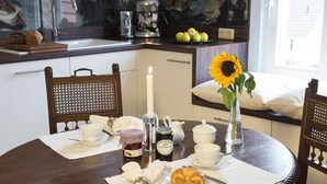 A dining table set with a candle, a sunflower vase, a croissant, and a coffee pot. - Admiralssuite Wf-46 - Der Westflügel (Stolpe auf Usedom)