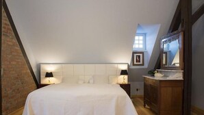 A bedroom with a large bed, two bedside lamps, a wooden dresser, and a mirror. - Admiralssuite Wf-46 - Der Westflügel (Stolpe auf Usedom)