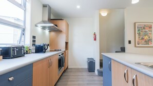 A modern kitchen with wooden cabinets, a stainless steel range hood, and a built-in oven. - Spacious Home Near CBD | SPA Pool | Parking | 3BR (Auckland)