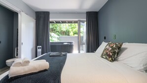 A hotel room with a large bed, a dark blue headboard, a white pillow, and a view of the outdoors. - Spacious Home Near CBD | SPA Pool | Parking | 3BR (Auckland)
