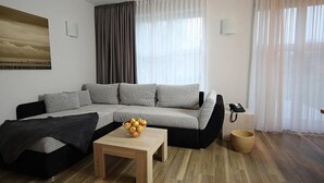 A modern living room with a grey sofa, a wooden coffee table with fruit, and a black sofa. - Storchennest Wf-52 - Der Westflügel (Stolpe auf Usedom)