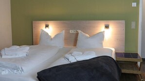 A hotel room with a bed, two bedside lamps, a nightstand, and a woven basket. - Storchennest Wf-52 - Der Westflügel (Stolpe auf Usedom)