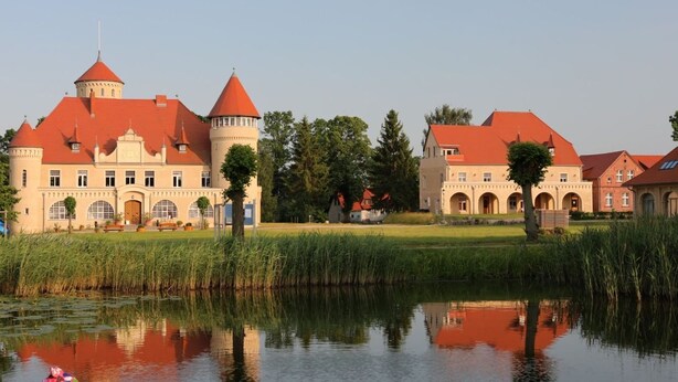Un grand château doté de nombreuses tours et entouré de douves.