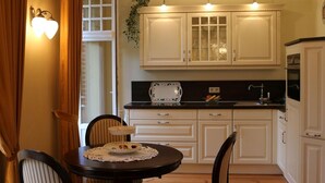 A compact kitchen with white cabinets, a black countertop, and a dining table with chairs.