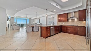 Una cocina moderna con una isla curva, electrodomésticos de acero inoxidable y un amplio ventanal con vistas.