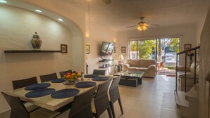 Una sala de estar moderna con comedor, que incluye un sofá, televisor y una escalera.