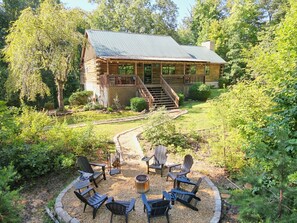 Une cabane en rondins avec un porche, un espace salon extérieur et un foyer.