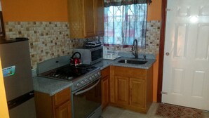 A compact kitchen with a stove, microwave, and sink.