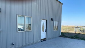 A single-story building with a metal exterior, a white door, and two windows. - Unique Farmhouse in quiet country setting with beautiful views (La Crosse)