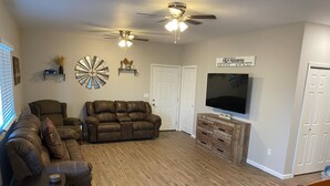 A living room with a sectional sofa, a recliner, a TV, and a ceiling fan. - Unique Farmhouse in quiet country setting with beautiful views (La Crosse)