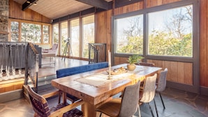 A spacious dining area with a wooden table, chairs, and a blue bench. - Asher by AvantStay | Pool + Hot Tub | Stunning Views of the Blue Ridge Mountains (Asheville)