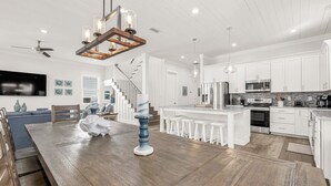 A spacious kitchen with white cabinets, a wooden dining table, and a central island.
