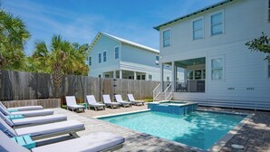 A backyard with a swimming pool, lounge chairs, and a wooden deck.