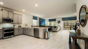 A modern kitchen with a central island, built-in microwave, and stainless steel appliances. - Grand 8BR Villa by Disney | Pool and Games Room (Kissimmee)