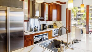 Une cuisine moderne dotée d’appareils électroménagers en acier inoxydable, d’armoires en bois et d’un plan de travail en marbre.