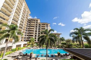 Un hotel con piscina rodeada de palmeras y sillas de descanso.