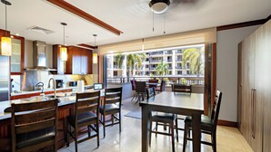 Une cuisine moderne avec un coin repas, de grandes fenêtres et une vue sur un immeuble doté de balcons.